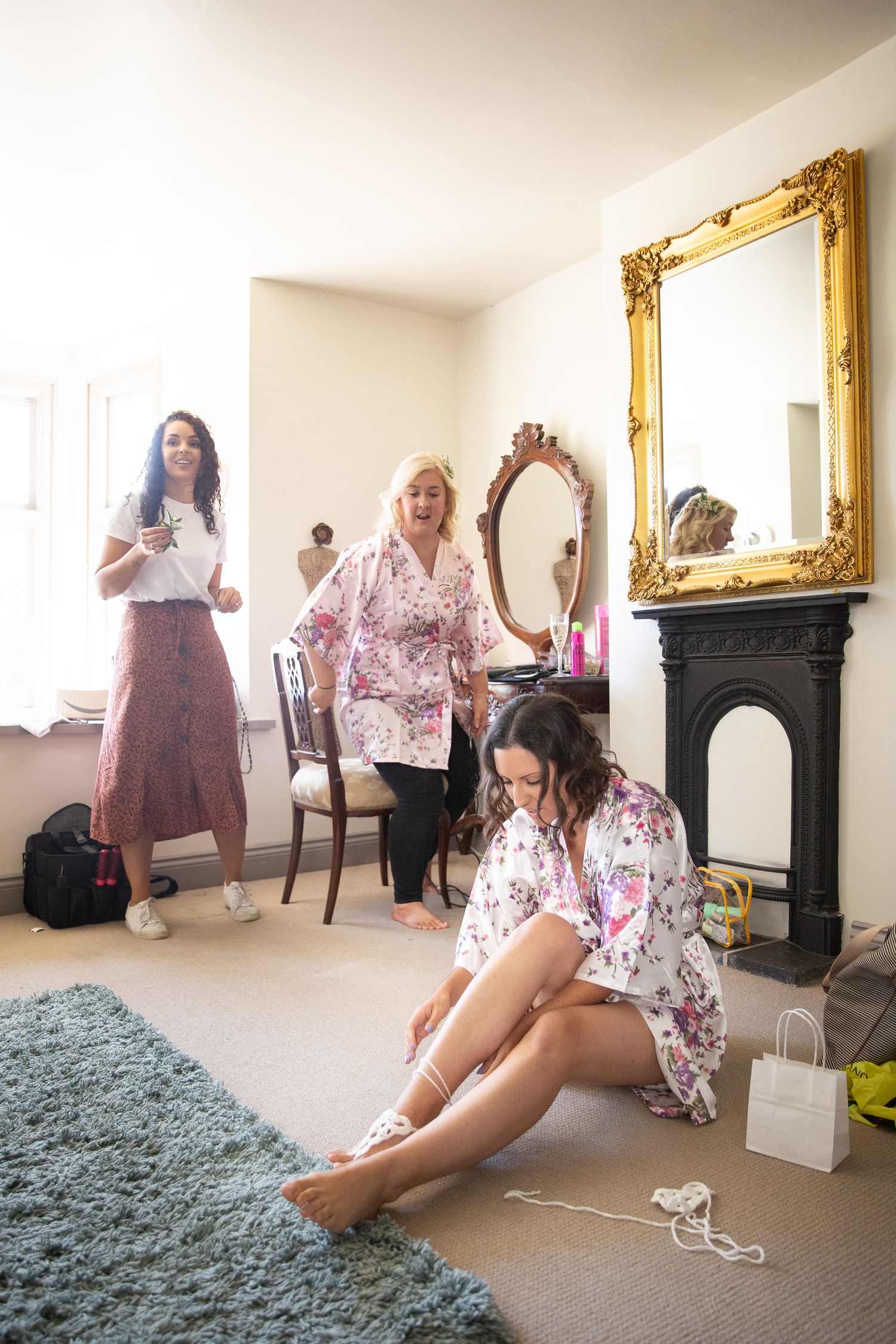 Getting ready scene with matching floral robes in a room with ornate gold mirrors.