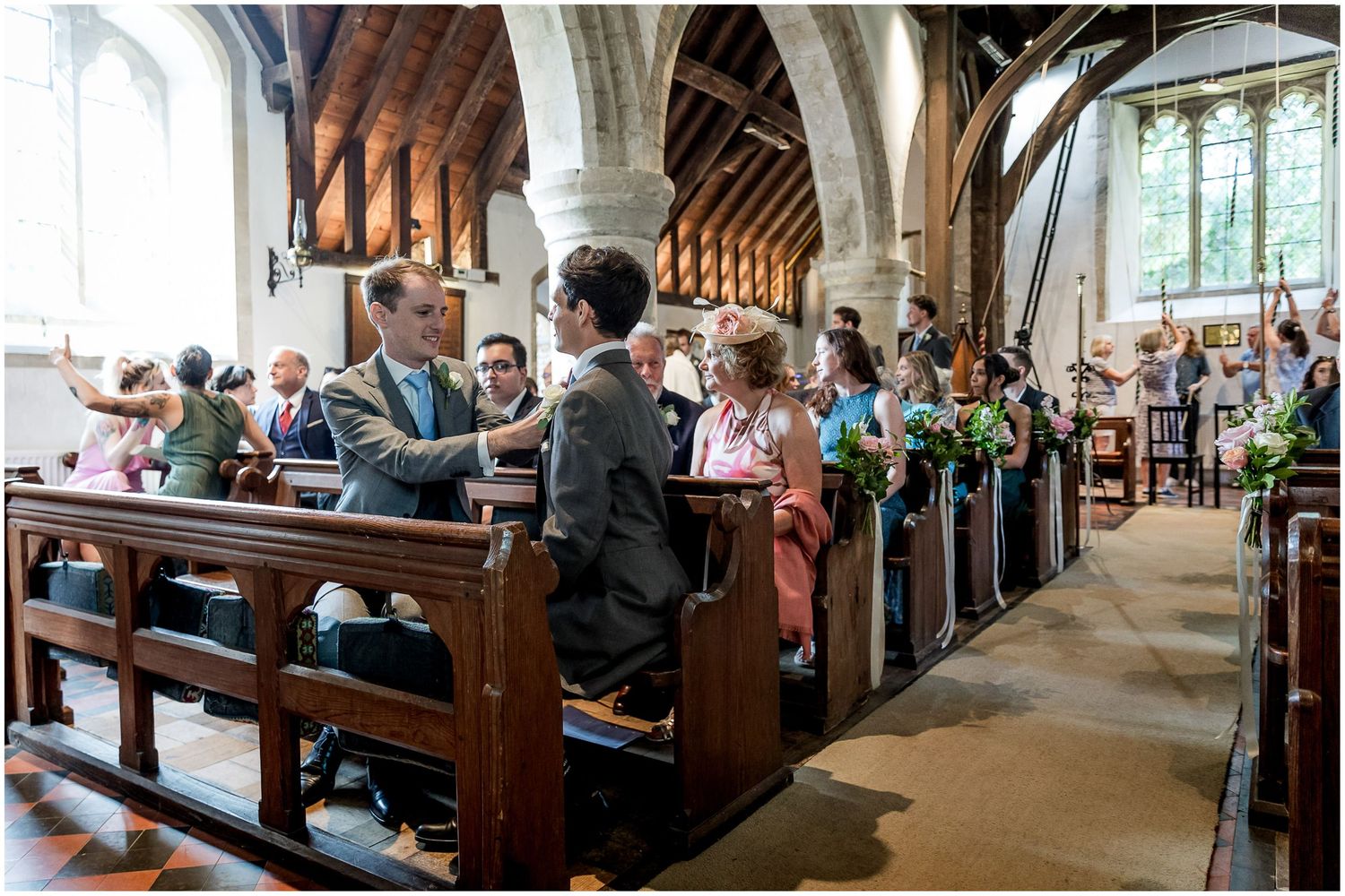 Interior of historic church with wooden beams and pews filled with wedding guests.
