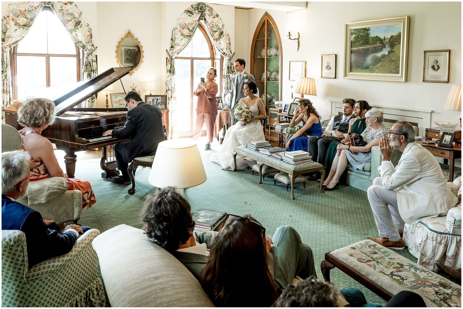 Wedding guests gathered in an elegant room with ornate decor and large windows.