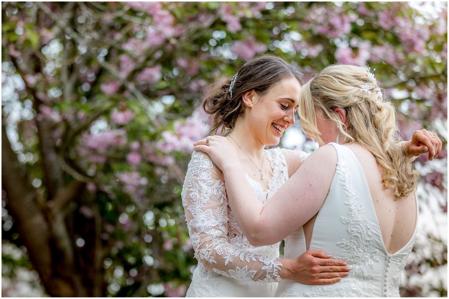 Tender moments shared between couple among flowering spring trees.
