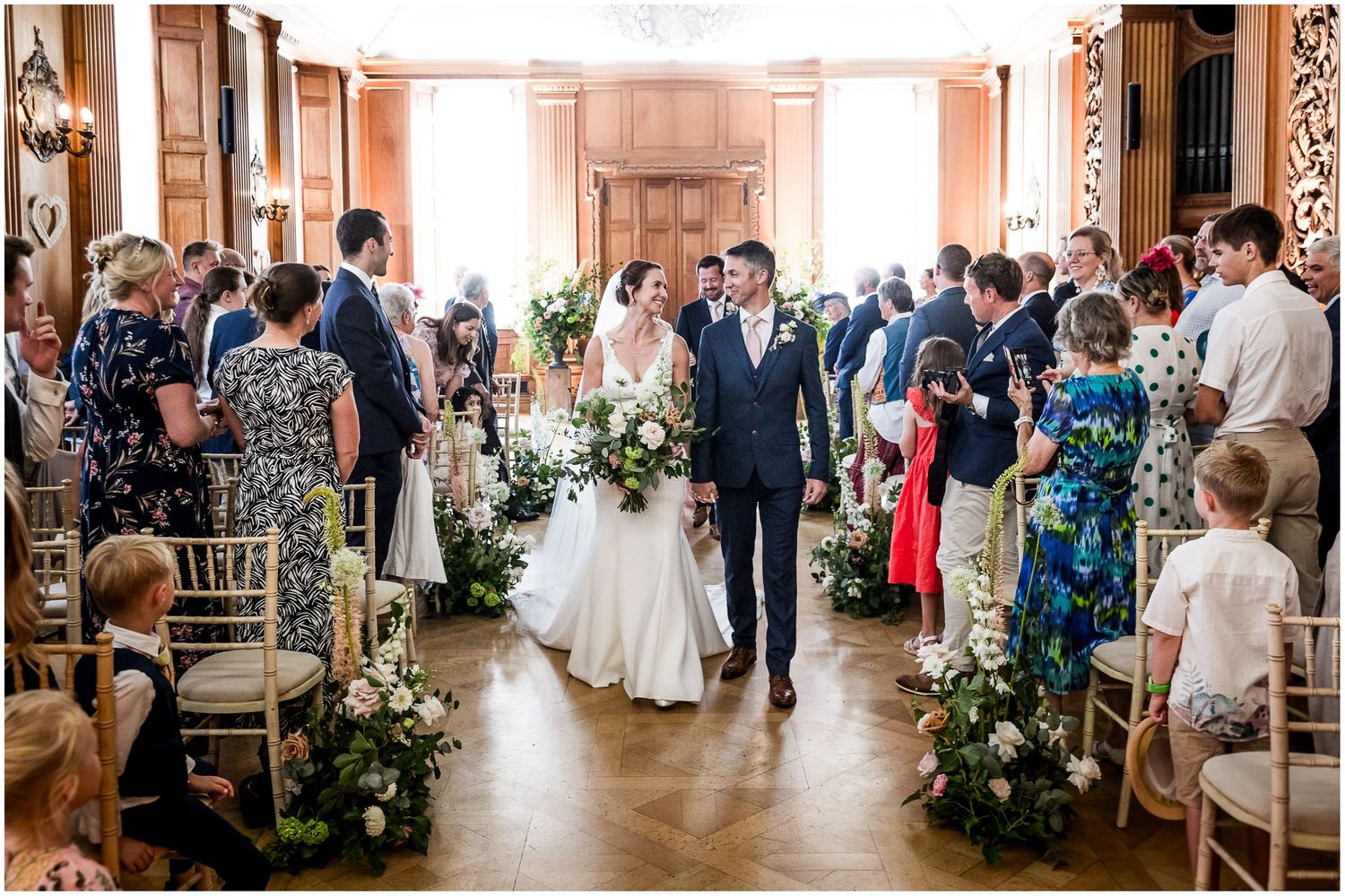 Bride and groom walk down the aisle at Walhampton School after a wedding ceremony in the main hall