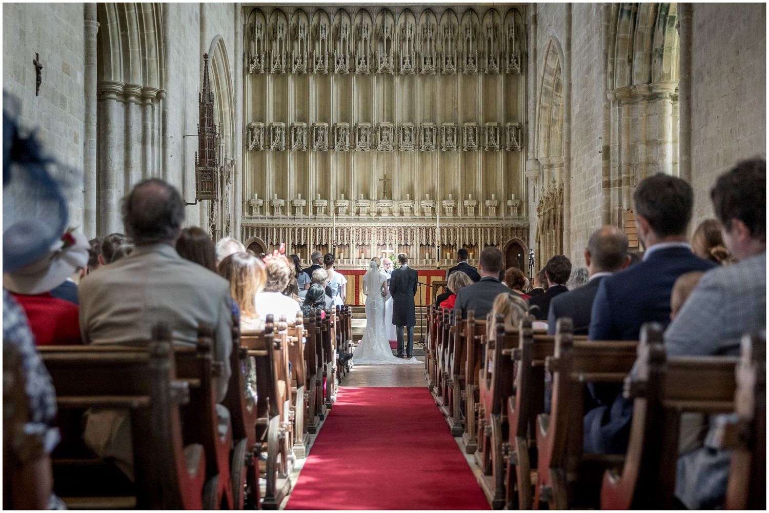 Long view down church aisle with ornate gothic architecture and red carpet.