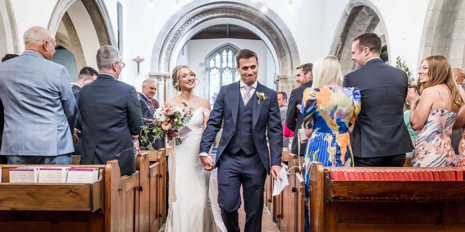 Wedding guests mingling in church aisle after ceremony.