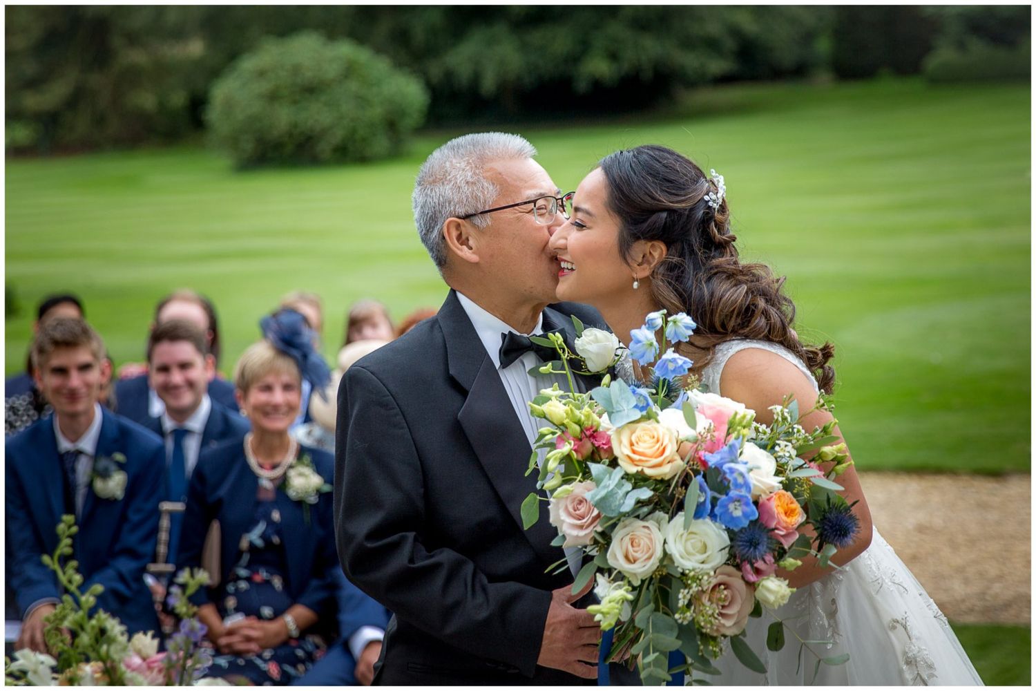 Elegant outdoor wedding ceremony with floral arrangements and guests gathered on a sunny day.