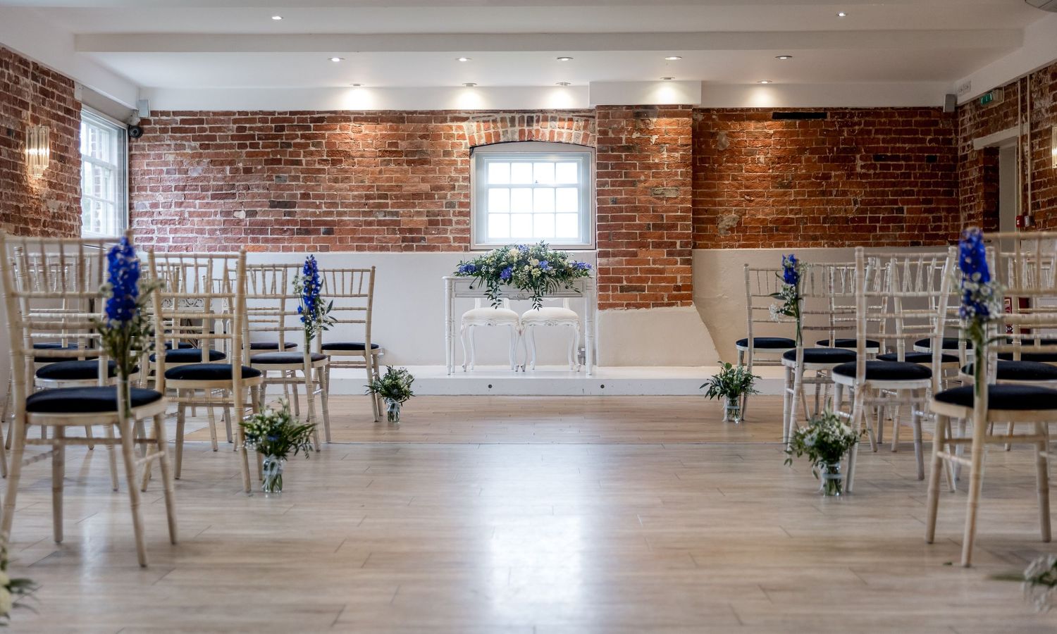 Large rustic wedding venue with exposed brick walls and rows of chairs set up for ceremony.