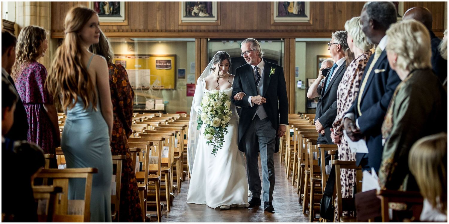 Wedding ceremony procession through an elegant church with wooden details and natural light.