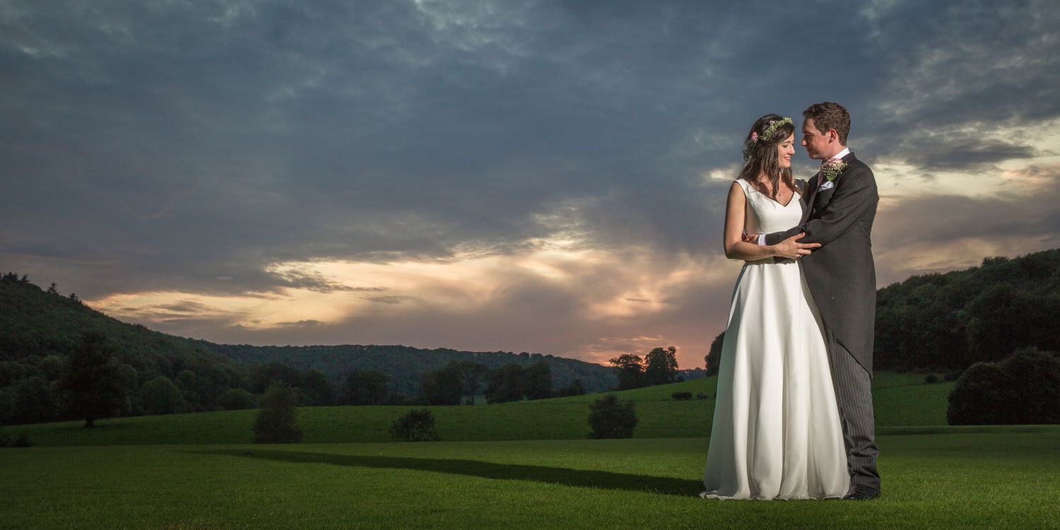 Dramatic sunset sky provides backdrop for an outdoor wedding ceremony.