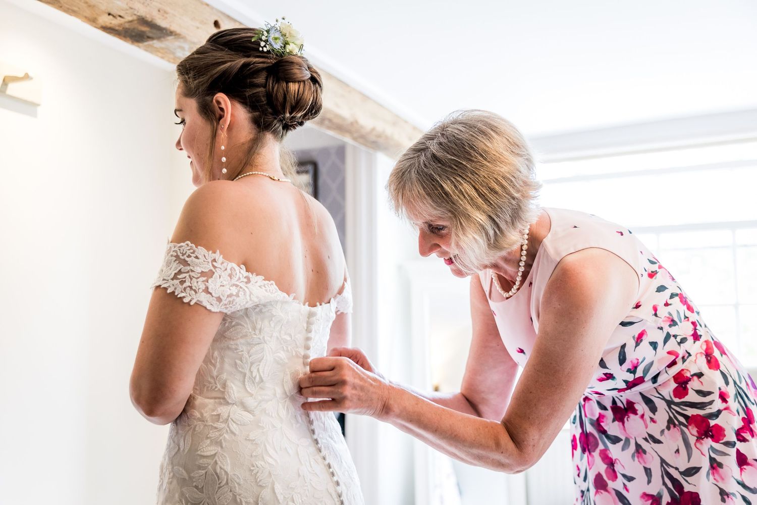 Women in white and floral dresses prepare for formal occasion.
