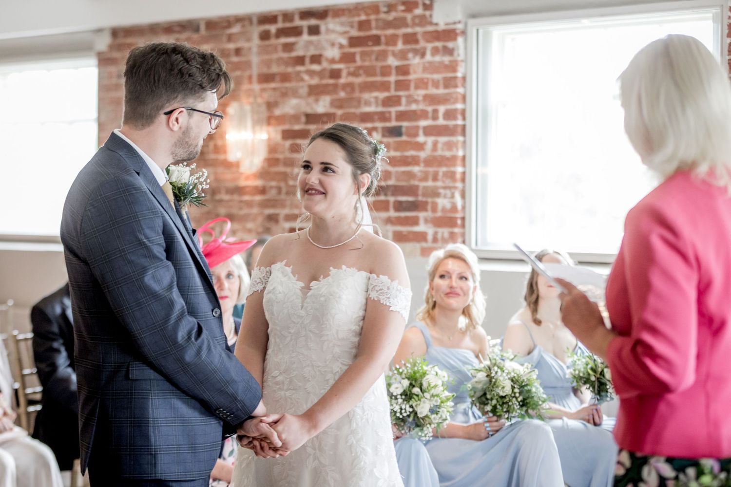 Wedding ceremony in a rustic brick venue with natural light streaming through windows.
