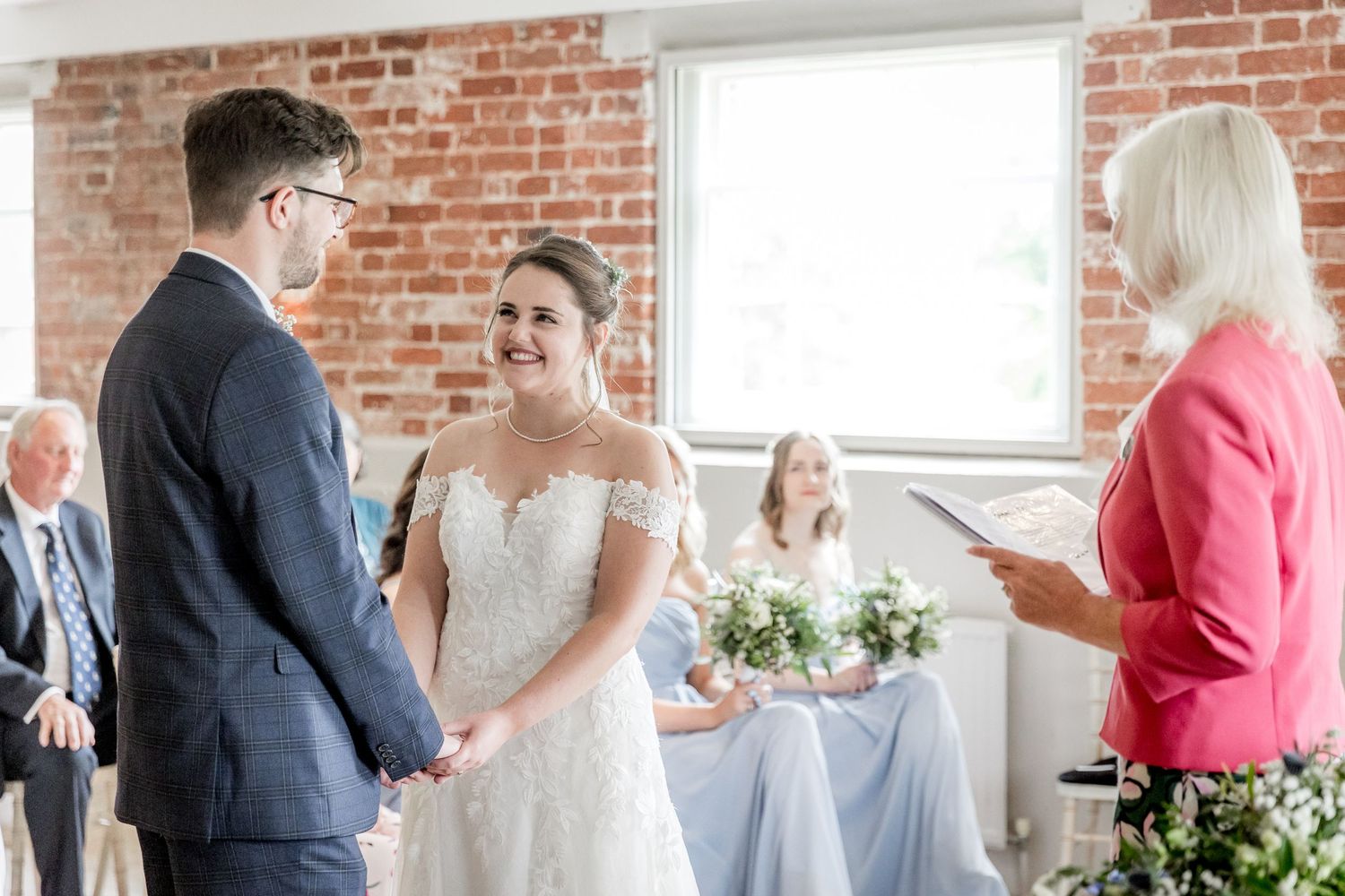 Bright wedding ceremony scene with exposed brick walls and natural lighting.