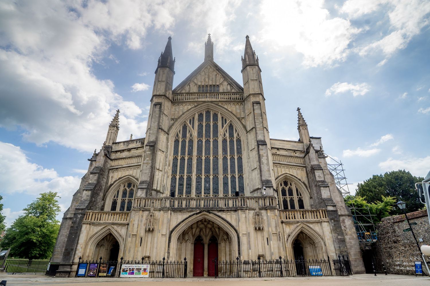 Panoramic view of a Gothic cathedral exterior with towering spires against cloudy sky.