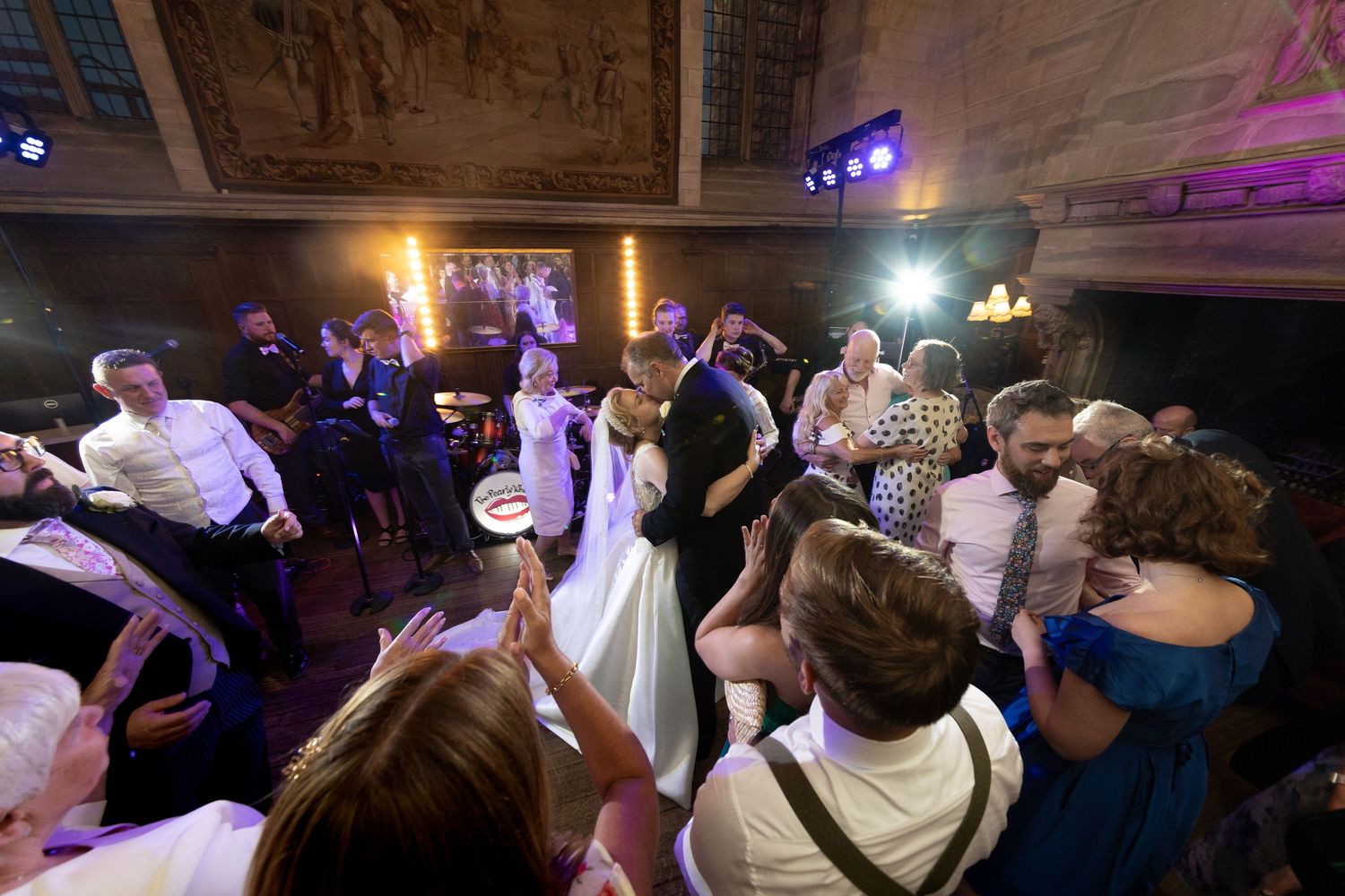 Energetic dance floor scene at a wedding reception with colorful lighting and party atmosphere.