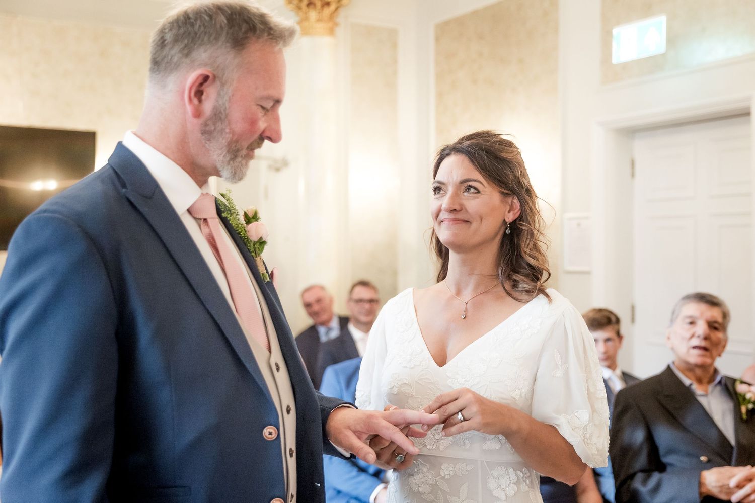 A couple exchanges vows during their wedding ceremony in a bright, sunlit room.
