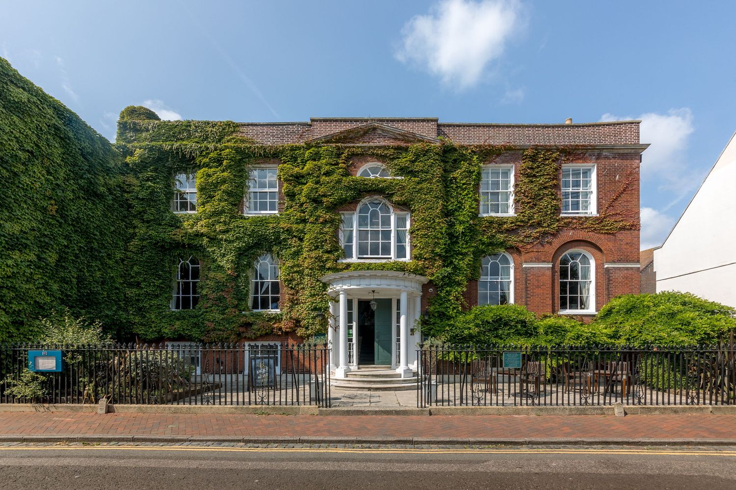 Panoramic view of a historic red brick Georgian style building with white trim and columns.