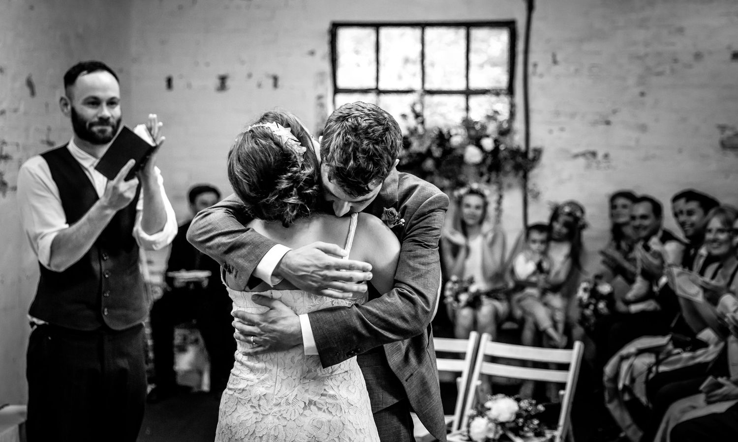 Black and white photo of guests celebrating and dancing at an indoor wedding reception.