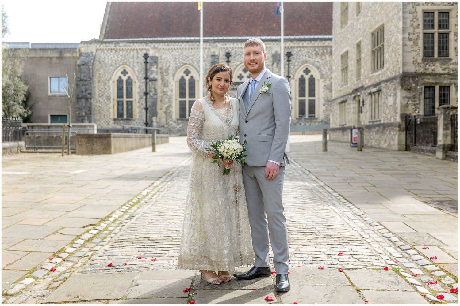 Wedding photographs taken on stone courtyard with rose petals scattered on ground.