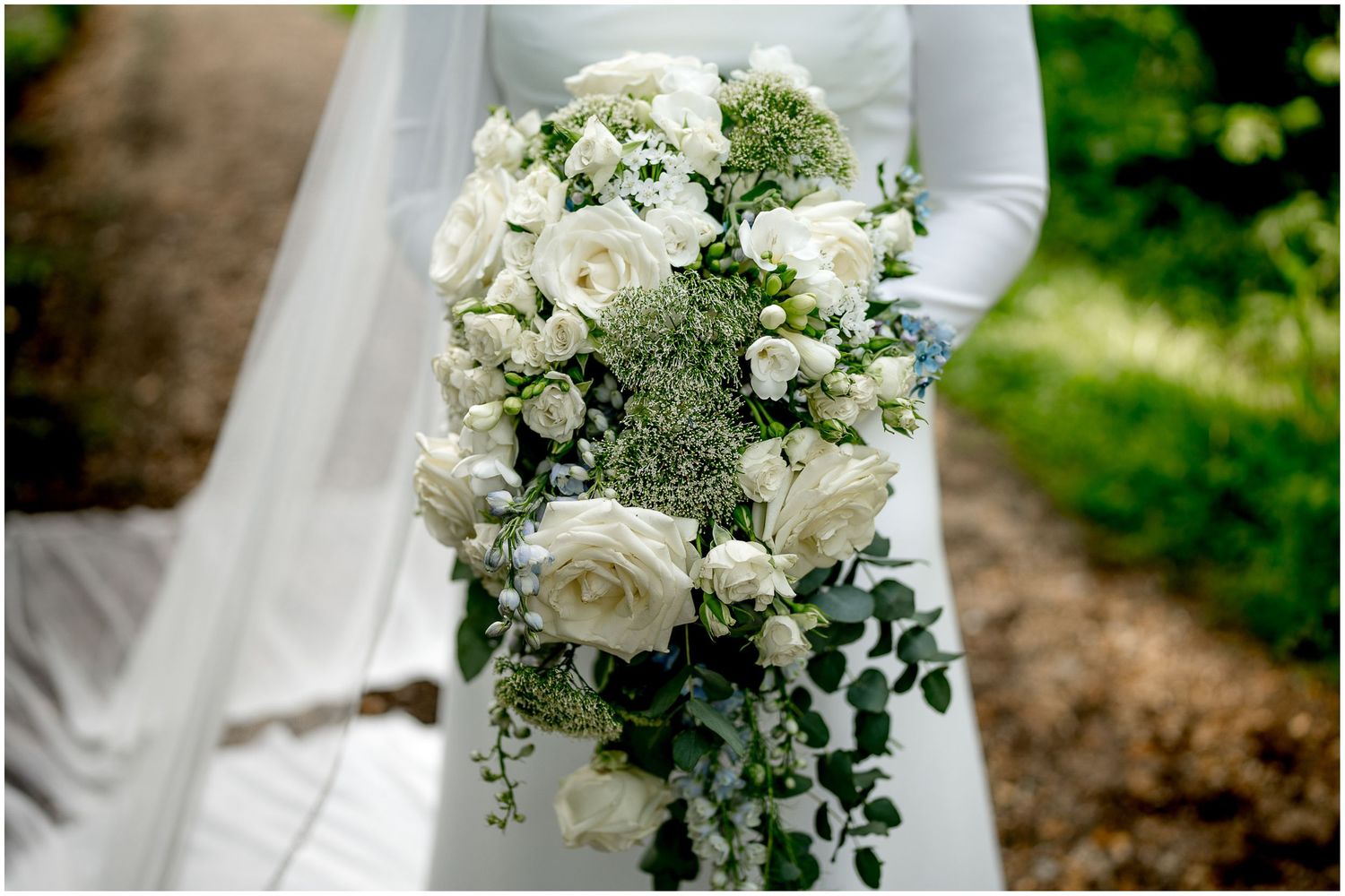 Elegant white rose and greenery wedding bouquet with cascading design.