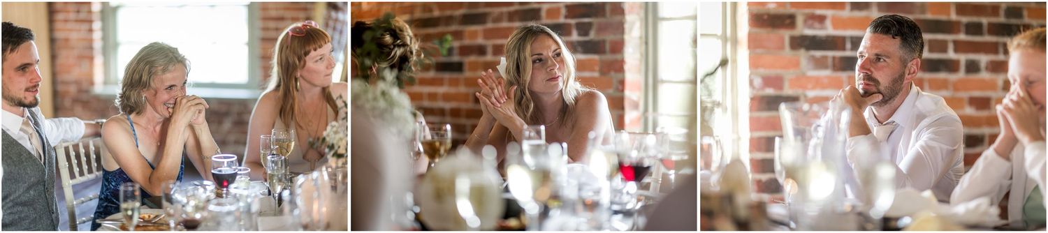 Wedding guests raise glasses in celebration at rustic brick-walled venue during reception toasts.