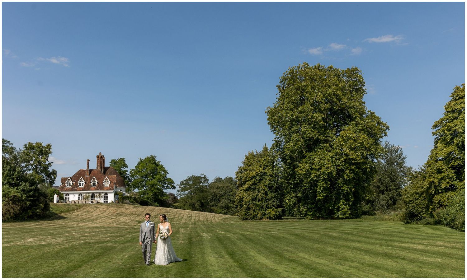 Panoramic view of a wedding venue with rolling green lawns and historic mansion.