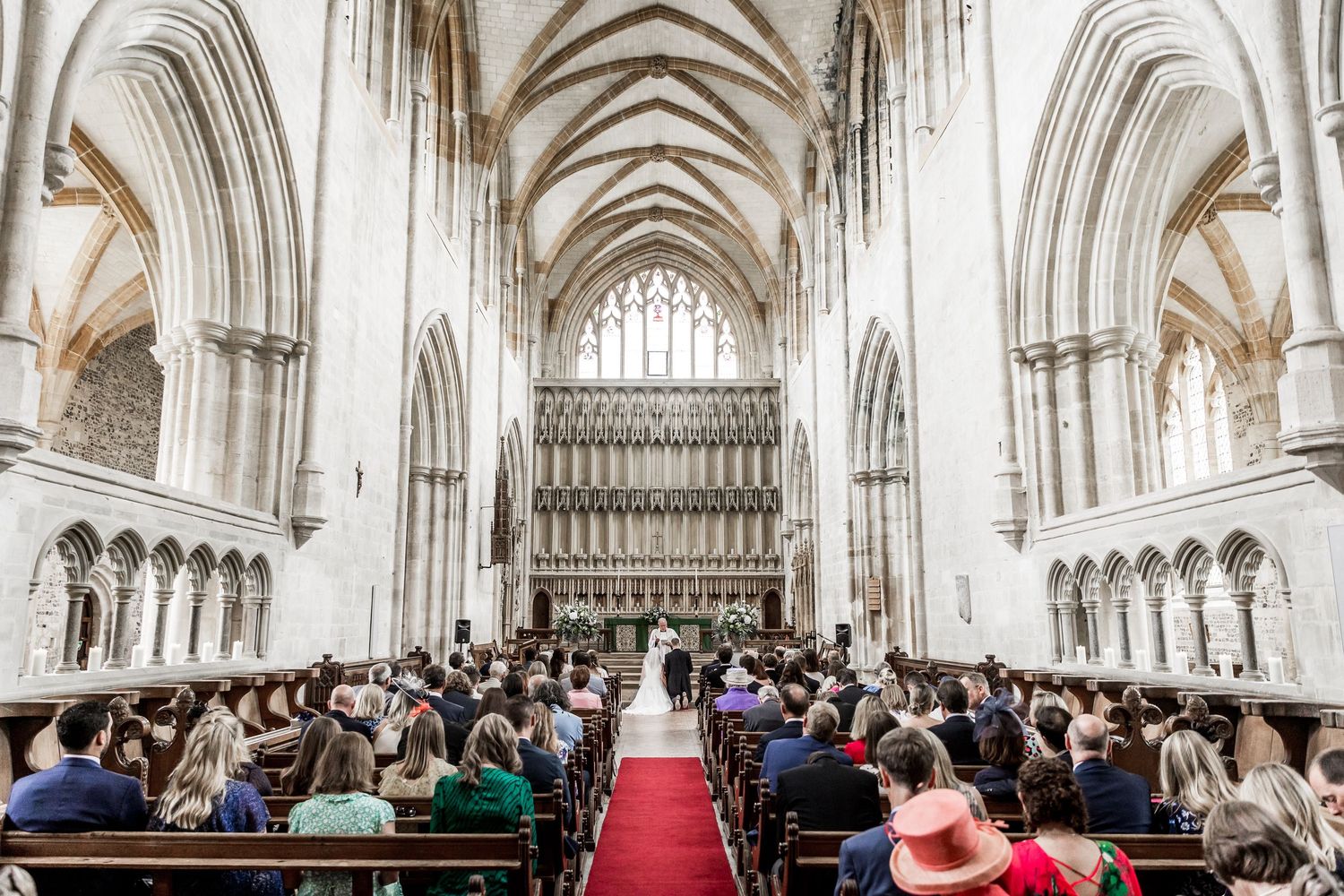 Interior panorama of a grand cathedral with vaulted ceilings and gothic architecture filled with wedding guests.
