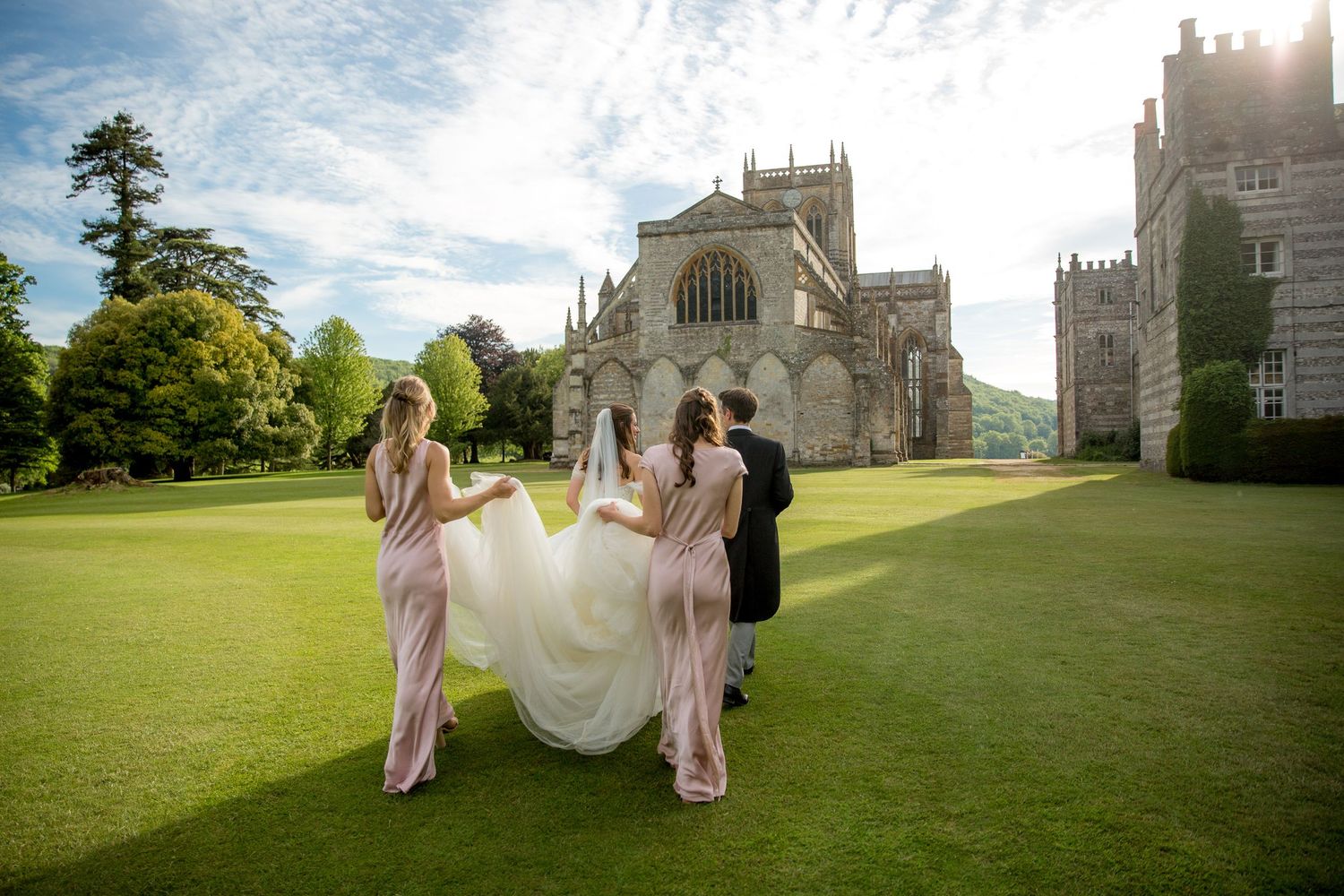 Wedding party on expansive lawn with historic cathedral building in background.