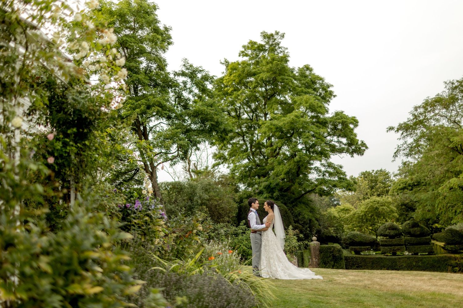 A panoramic view of a garden wedding ceremony setup with guests seated on both sides of an aisle.