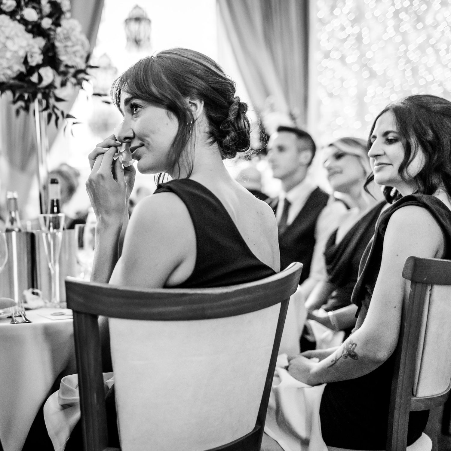 Wedding guests seated at elegant tables during an indoor reception celebration.