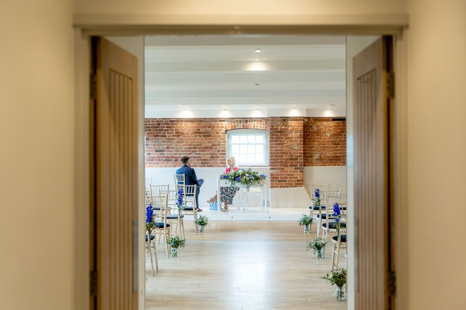 Long hallway view of elegant venue with brick walls and natural lighting.