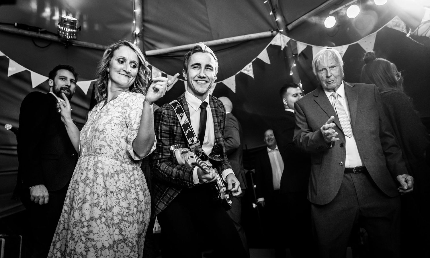Party guests dance and celebrate under festive lighting at an indoor event.