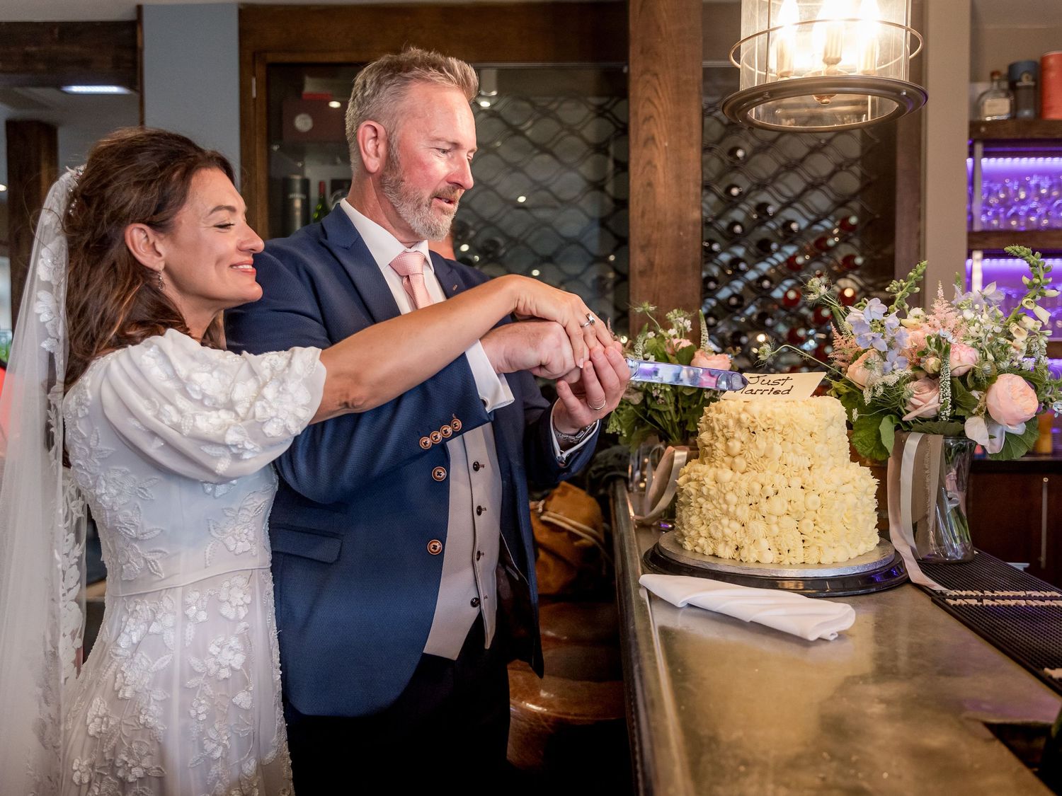 Wedding couple cutting their elegant tiered cake during reception celebration.