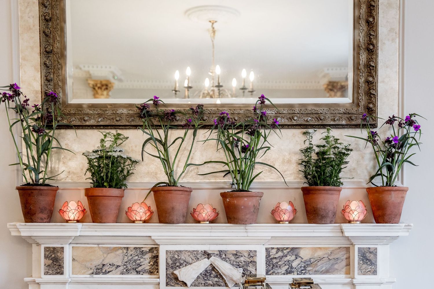 Decorative shelf display with terracotta pots and ornate gold-framed mirror in an elegant room.