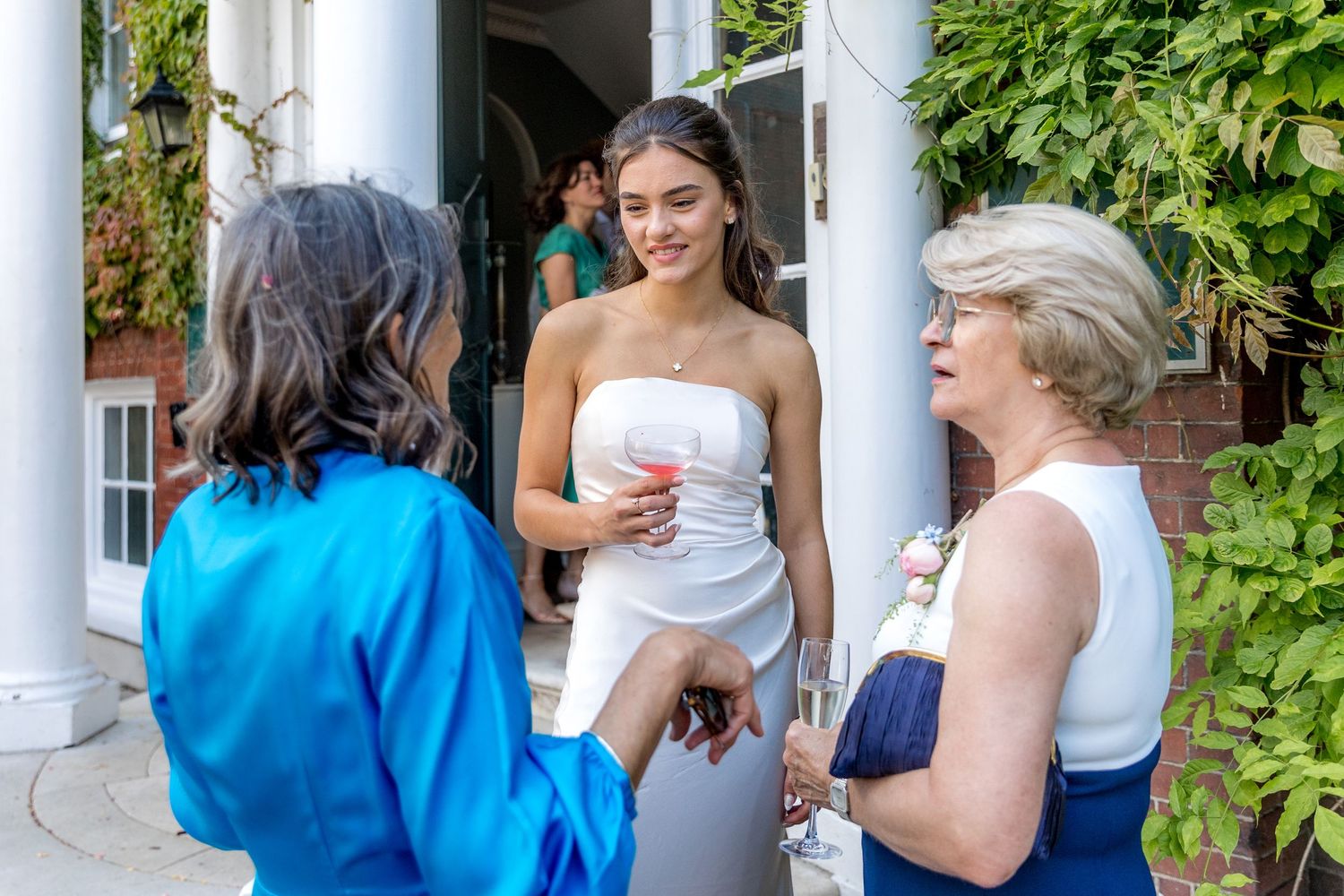 Wedding celebration captured in candid moments outside a historic building with white columns.