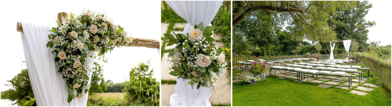 Elegant outdoor wedding decor with white floral arrangements and draped fabric at garden ceremony site.