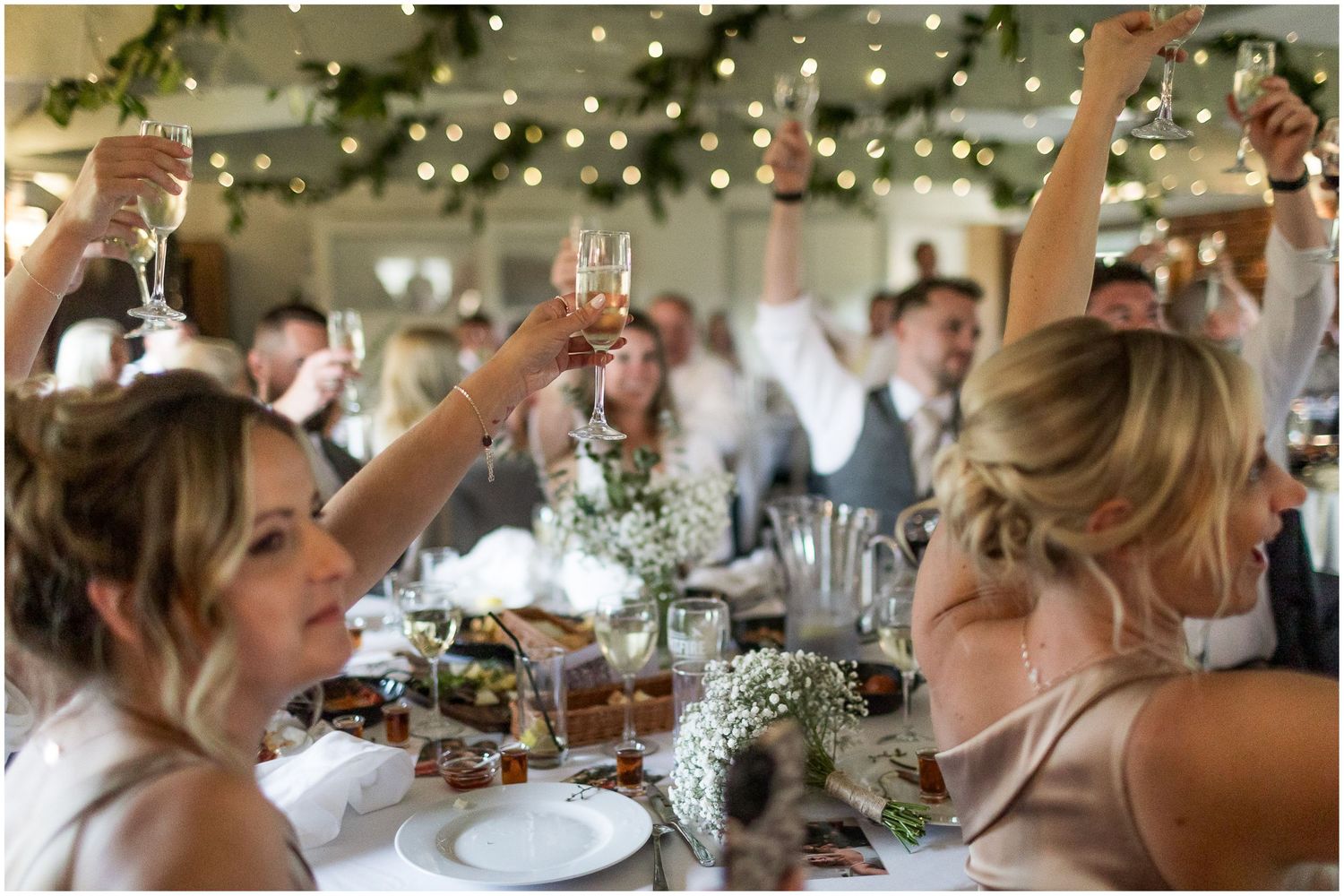 Elegant wedding reception table setting with twinkling lights and floral centerpieces.
