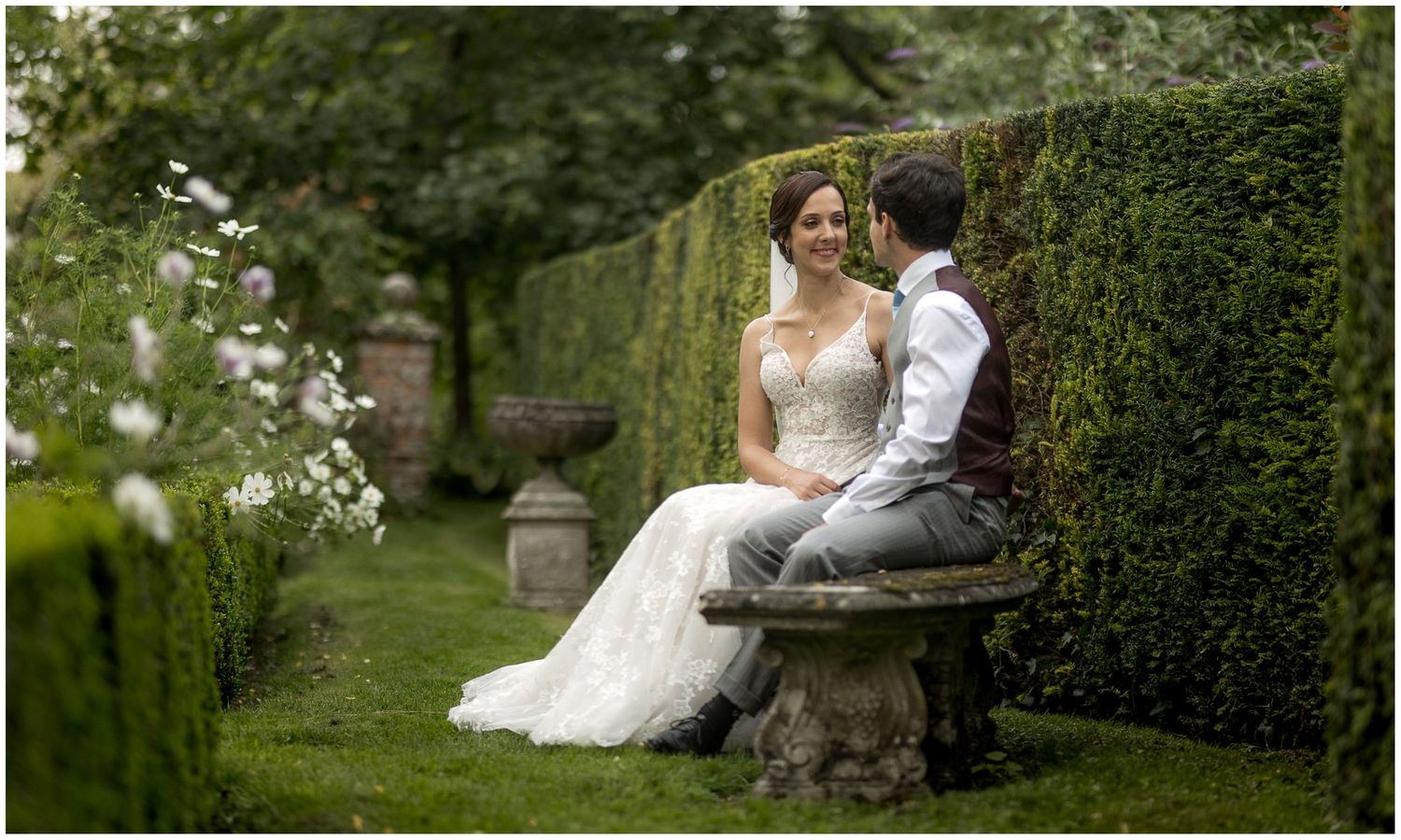 Couple shares intimate moments on a garden bench surrounded by elegant landscaping.