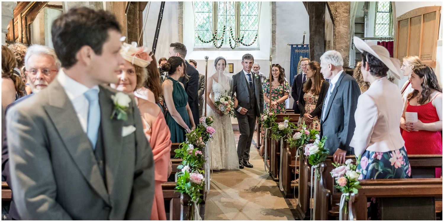Wedding ceremony in a rustic wooden church with natural light streaming through windows.
