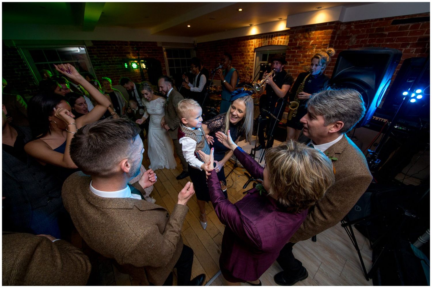 Wedding celebration with guests dancing under atmospheric lighting in a rustic venue.
