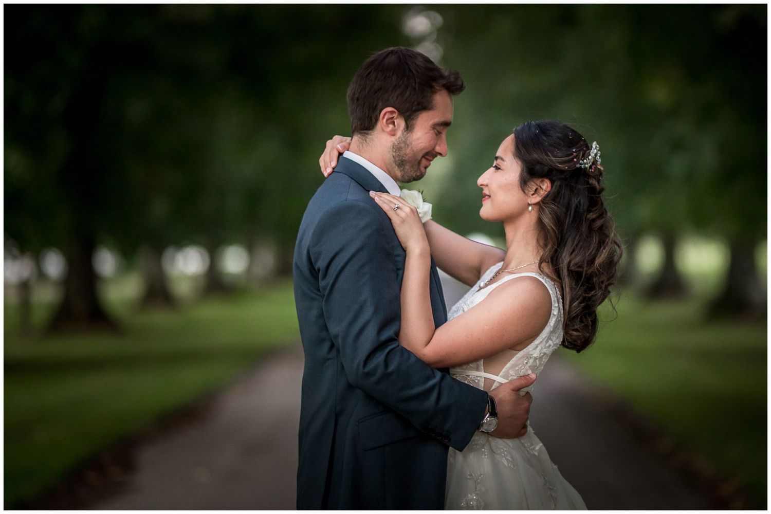 Newlyweds share intimate moments along a scenic garden walkway.