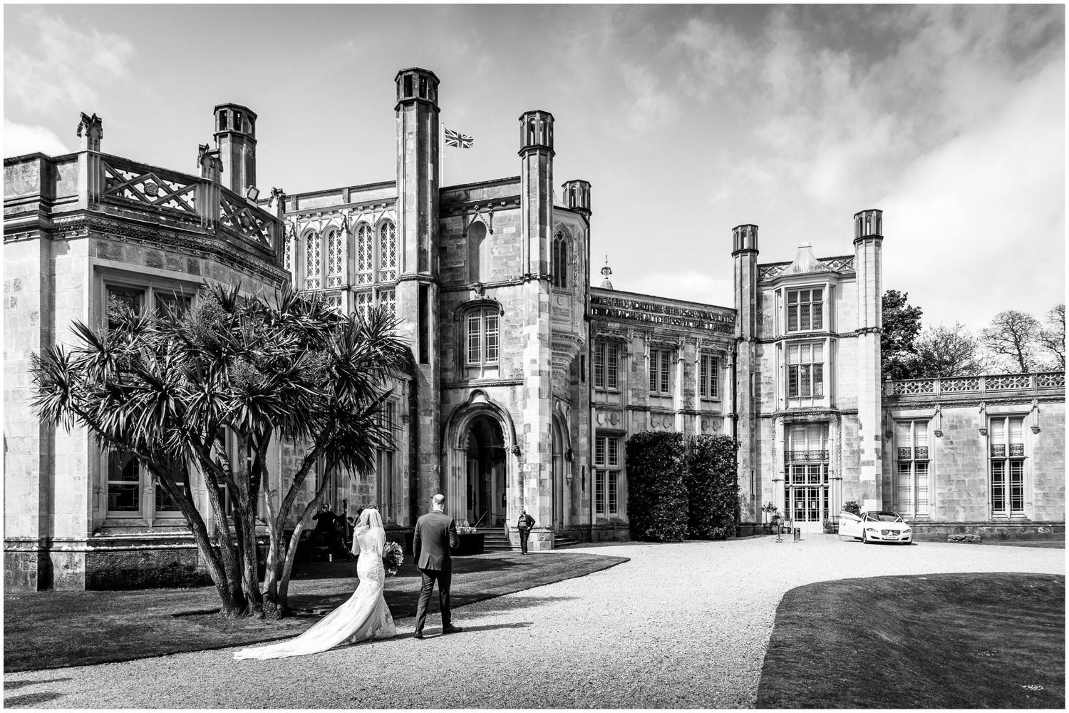 Highcliffe Castle wedding photography with bride and groom walking towards the New Forest wedding venue in Hampshire, with wedding car.