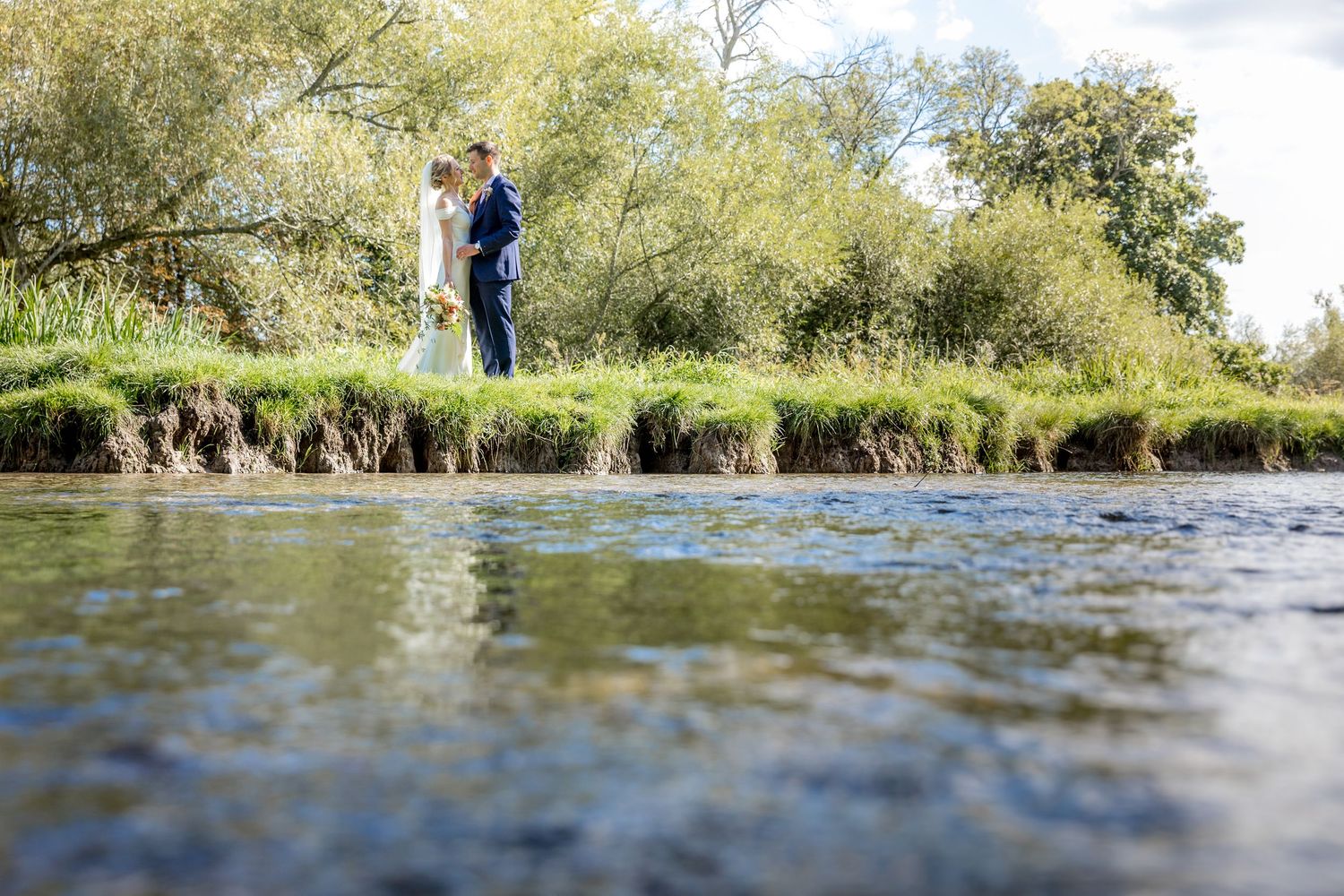 Scenic riverside wedding photos with natural water reflections.