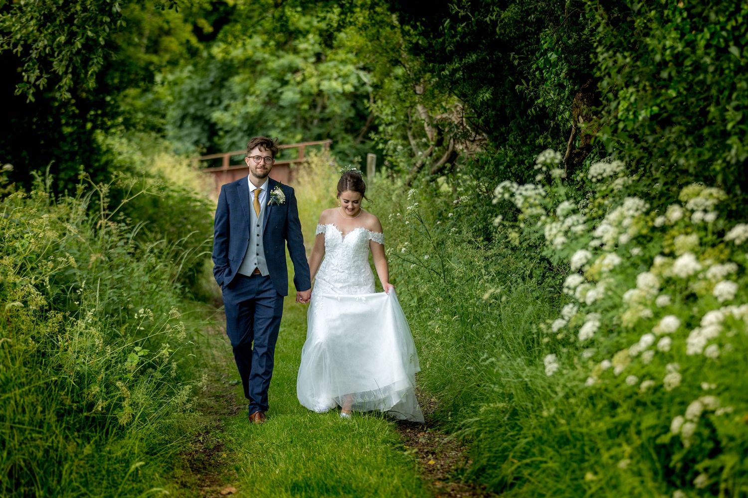 Couple walking through lush garden pathways during wedding photo session.