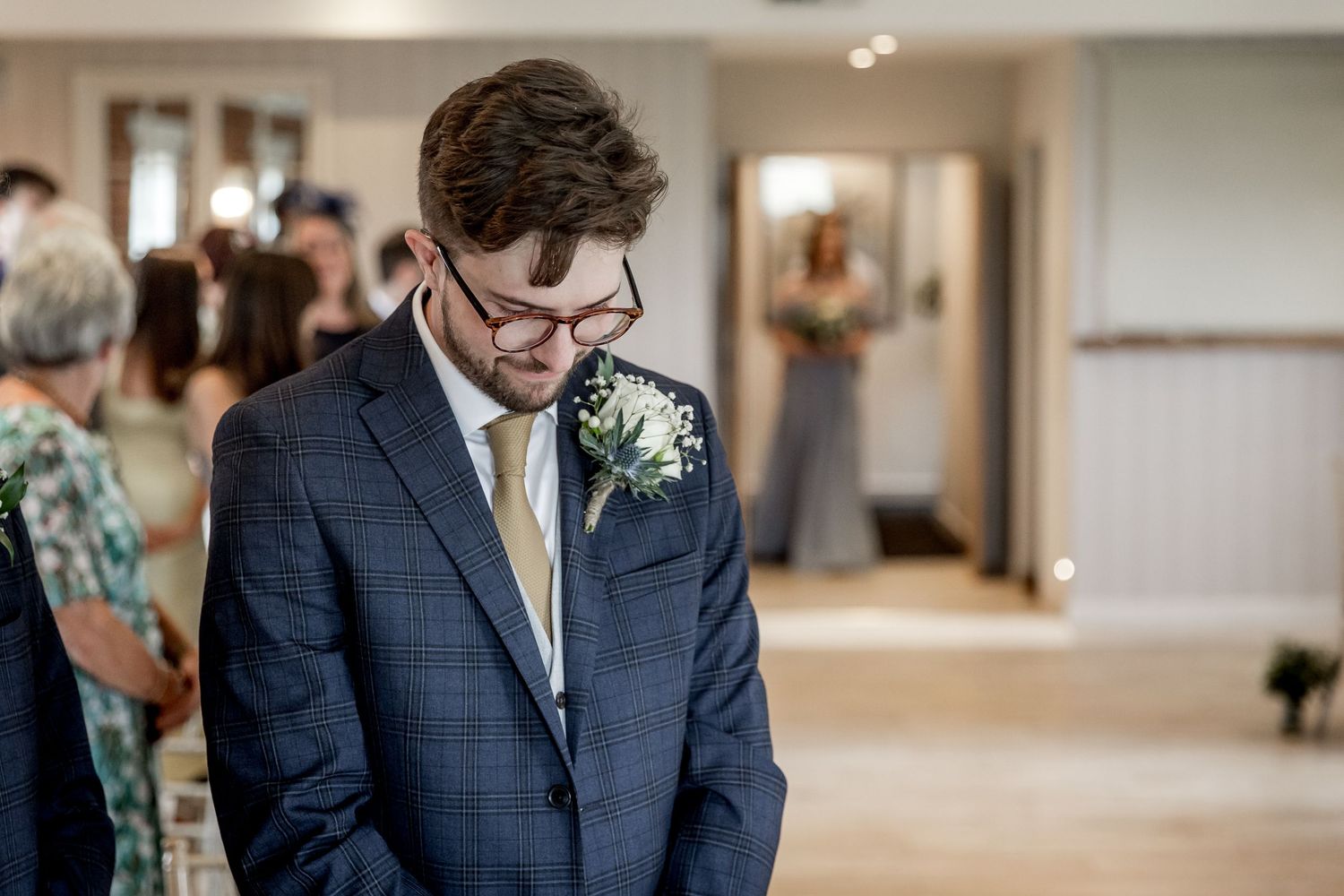 Groomsmen in formal attire preparing for wedding ceremony in a bright indoor space.