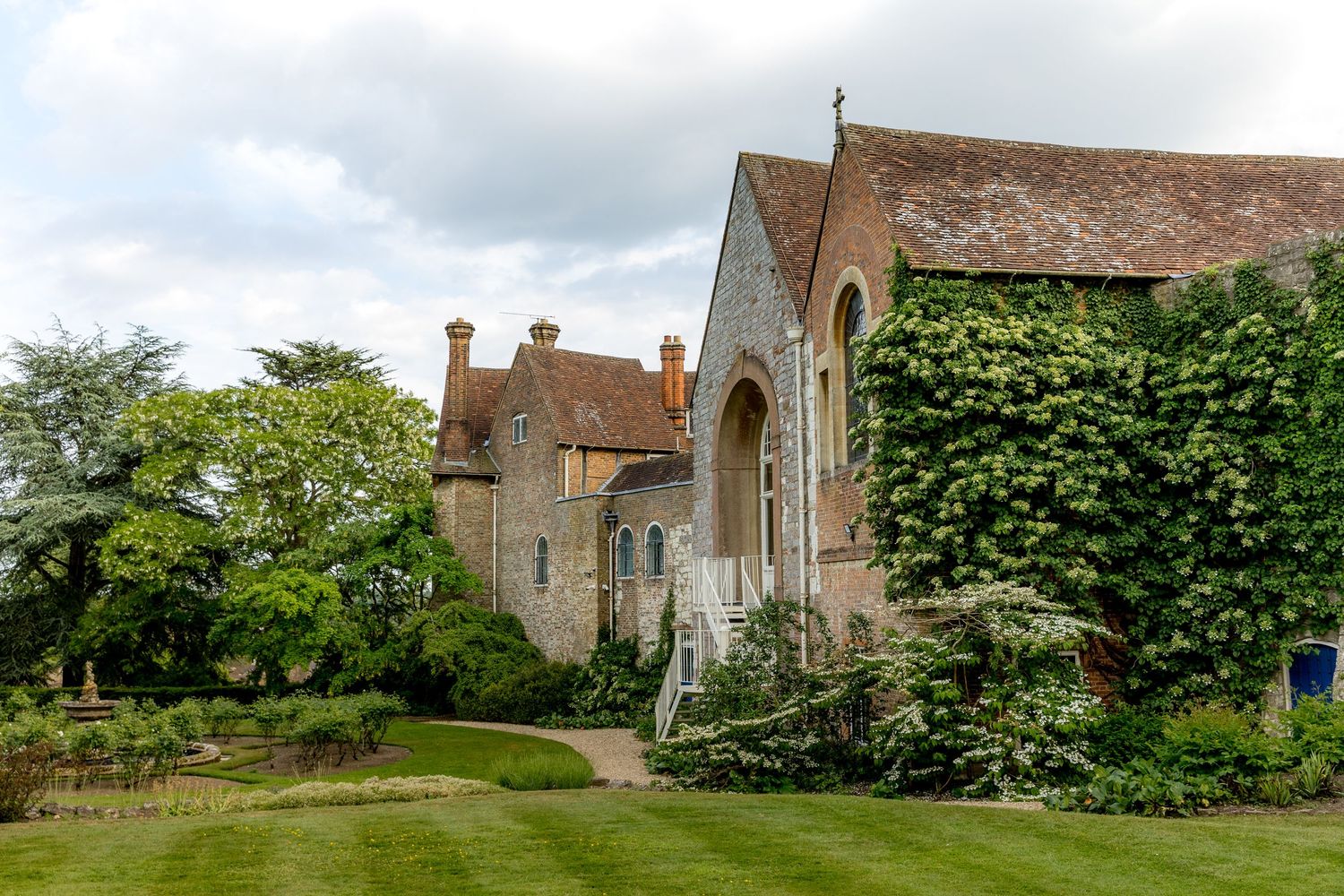 Panoramic view of an English countryside estate with stone buildings and lush gardens.