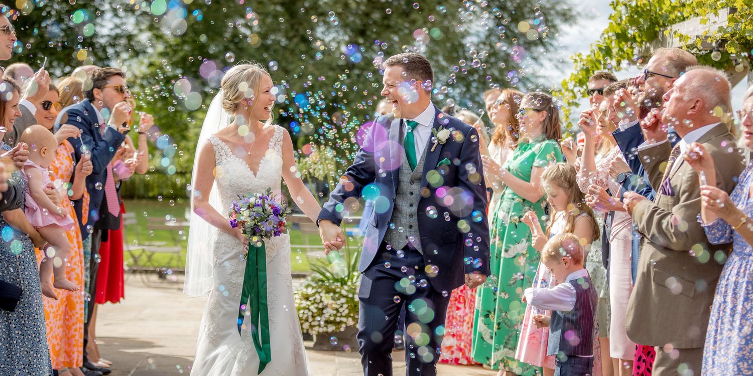 Wedding guests mingling outdoors in floral dresses and summer attire.