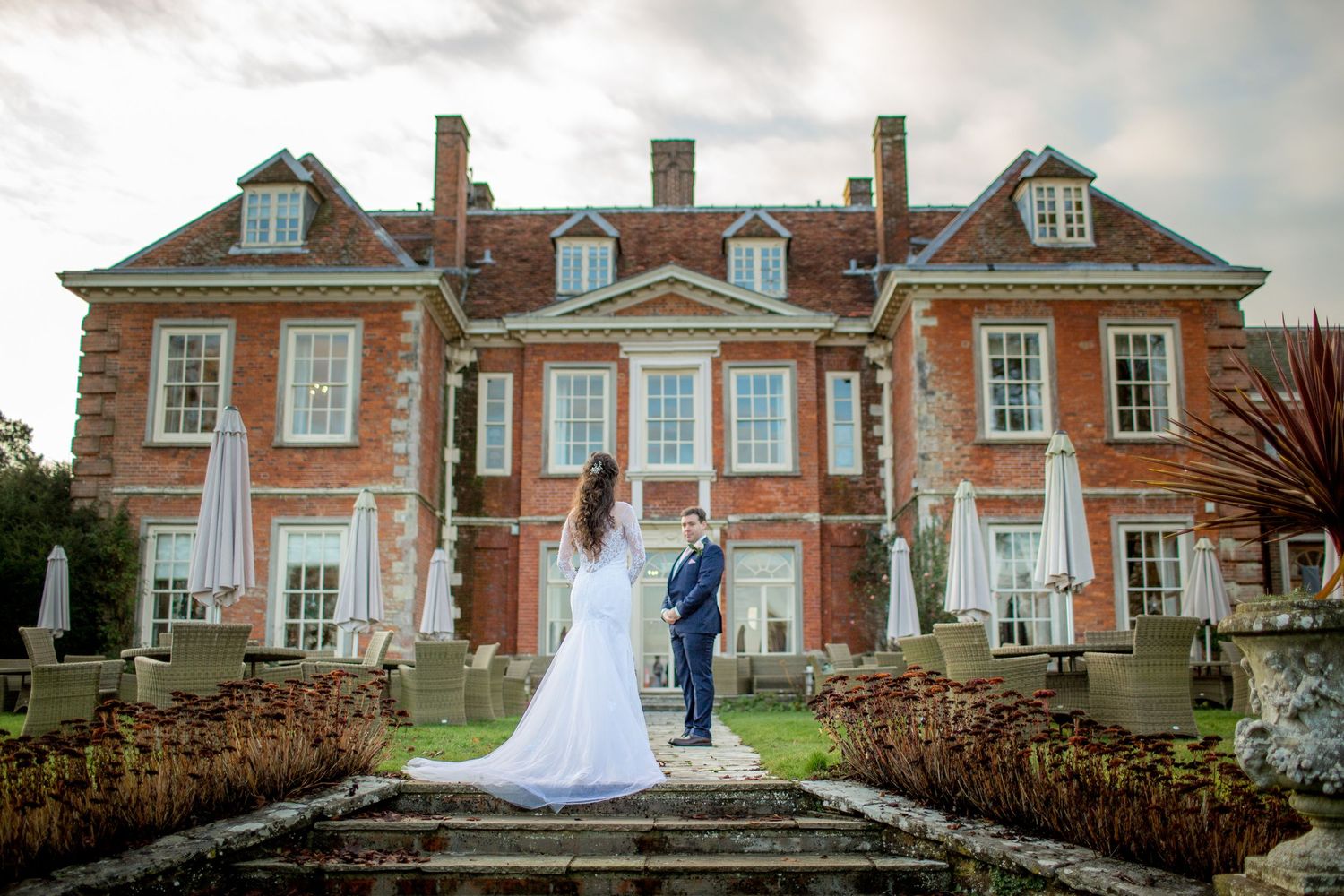 An elegant wedding scene at a historic red brick manor house with symmetrical architecture.