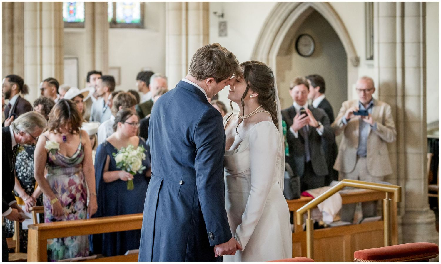 Traditional church wedding ceremony with guests seated in wooden pews under vaulted ceilings.