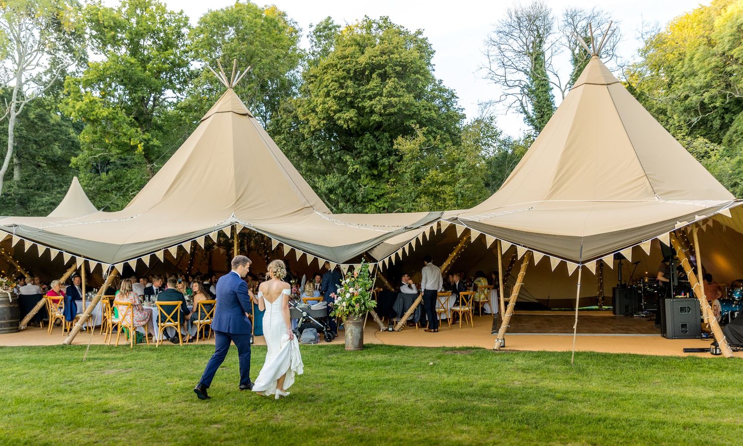Tipi tents arranged on a grassy hillside for an outdoor celebration.