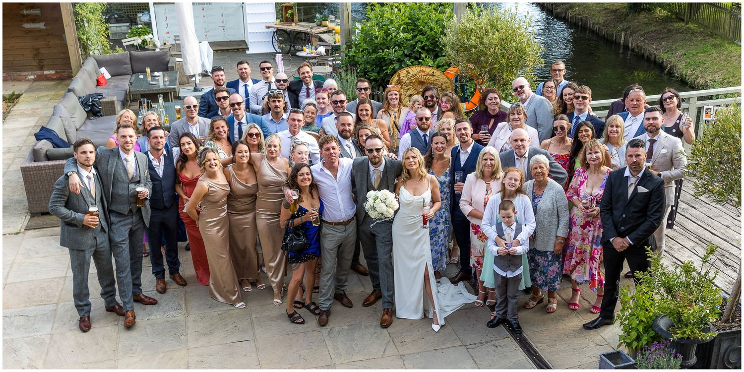 Large group photo of wedding guests gathered outside venue.