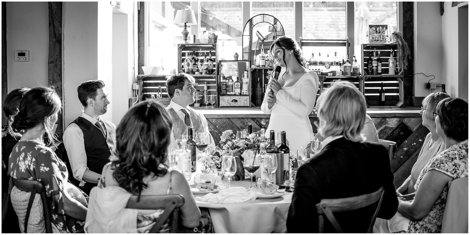 Black and white photo of guests enjoying a wedding reception at dining tables.