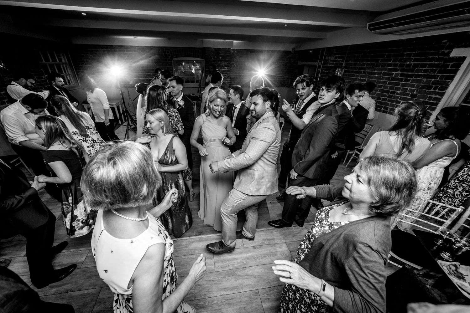 Wedding reception dance floor with dramatic lighting and couples dancing.